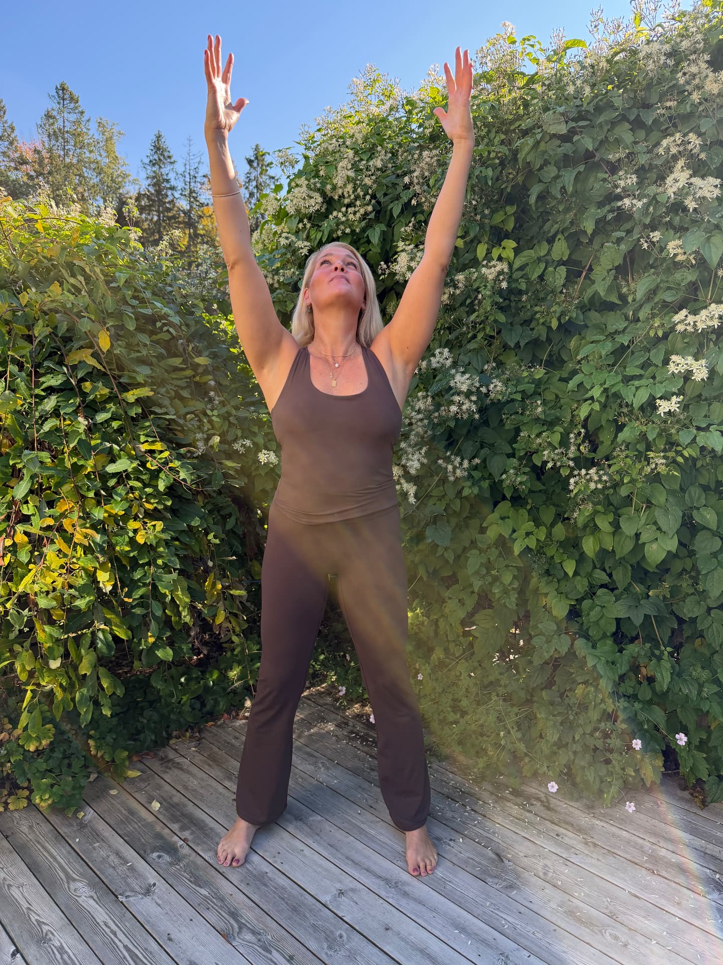 Johanna lyfter armarna mot skyn i qigong