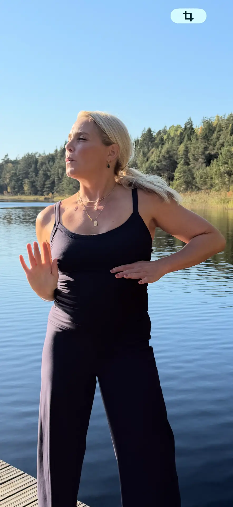 Johanna utövar qigong på en brygga vid en stilla sjö